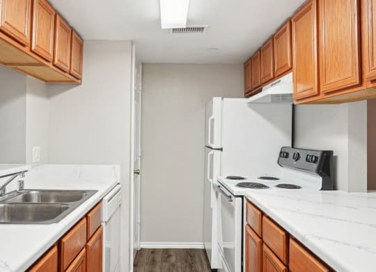Unfurnished A4 floor plan kitchen with white appliances and wooden cabinets Noel on The Parkway in Dallas, TX