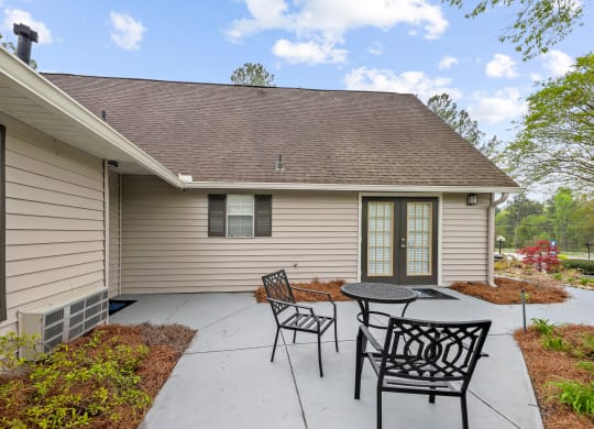 a patio with a table and chairs in front of a house