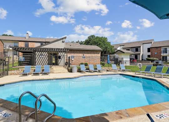 A swimming pool with a metal ladder at The Oaks of Denton Apartments in Denton, TX
