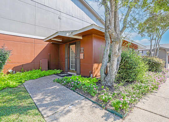 Leasing office with flowers growing next to the sidewalk at Orleans Square in Shreveport, LA