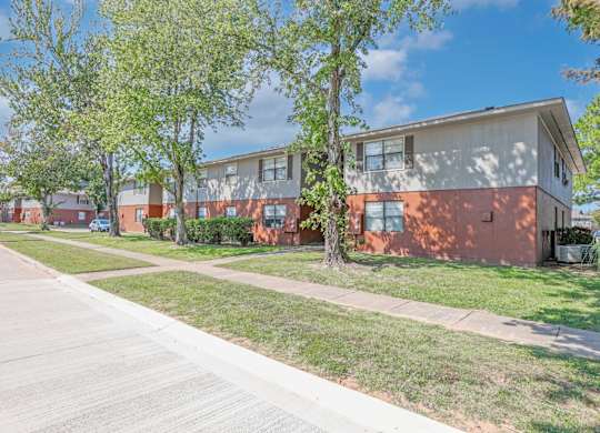 A sidewalk and lawn next to apartment buildings at Orleans Square in Shreveport, LA