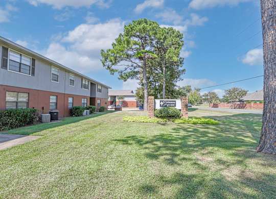 A tree stands in front of an "Orleans Square" sign and apartment buildings at Orleans Square in Shreveport, LA