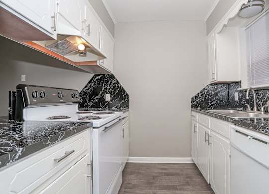 A kitchen with white cabinets, a stove top oven, sink, and dishwasher at Orleans Square in Shreveport, LA
