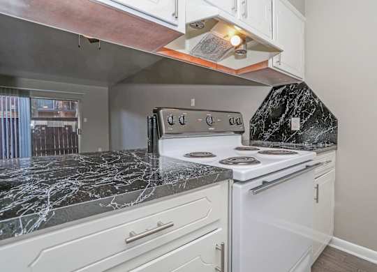 A kitchen with a white oven/stove and a dark marble countertop at Orleans Square in Shreveport, LA