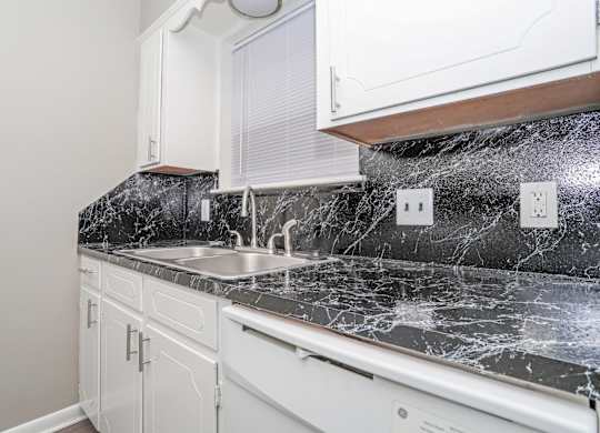 A kitchen with a marble countertop and white cabinets at Orleans Square in Shreveport, LA