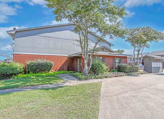The leasing office with a grey roof and a tree in front at Orleans Square in Shreveport, LA