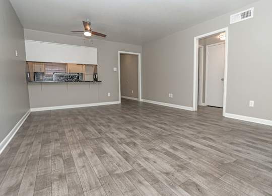 A living room with a ceiling fan and light, and a wooden floor at Orleans Square in Shreveport, LA