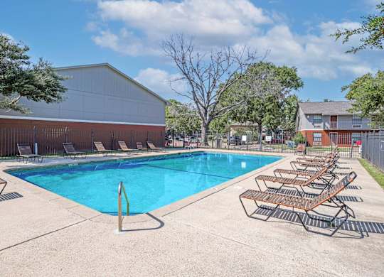 A pool with sun loungers and apartment buildings in the background at Orleans Square in Shreveport, LA