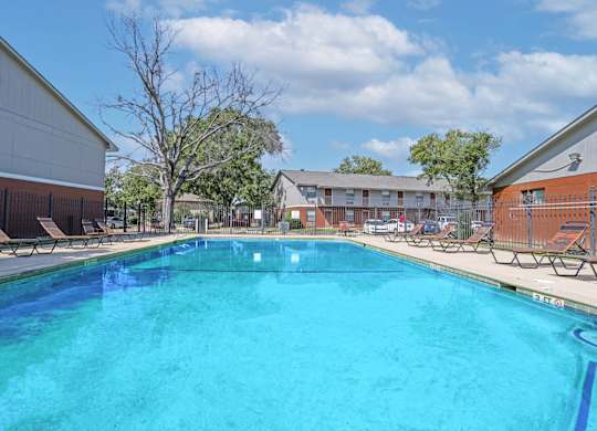 A large swimming pool with lounge chairs and apartment buildings in the background at Orleans Square in Shreveport, LA