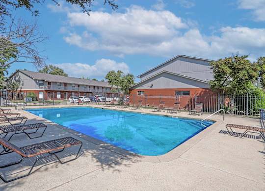 A swimming pool surrounded by lounge chairs and a fence at Orleans Square in Shreveport, LA