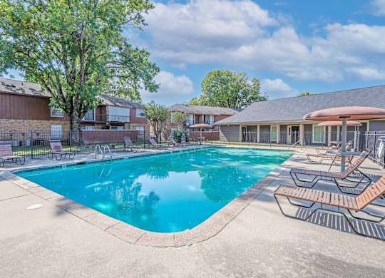 A swimming pool surrounded by a concrete patio and lounge chairs at Orleans Square in Shreveport, LA