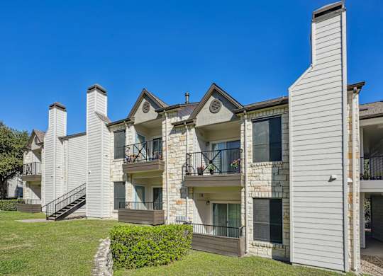 Row of our apartment buildings with balconies and a clear blue sky at On the Green apartments in Austin, TX