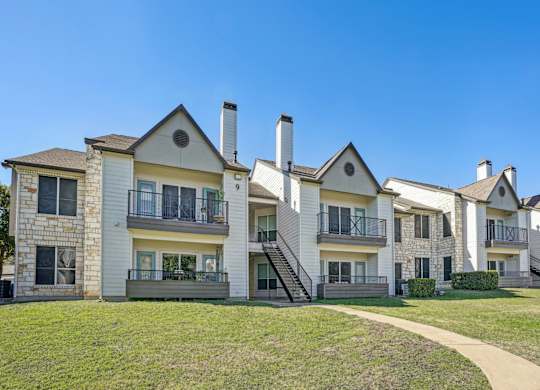 A row of apartments with balconies and staircases leading to the second floor at On the Green apartments in Austin, TX