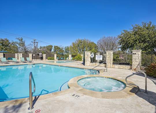 Our sparkling pool with a hot tub and poolside seating at On the Green apartments in Austin, TX