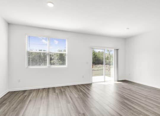 a spacious living room with white walls and hardwood floors