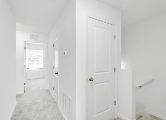 a hallway in a home with white walls and carpet