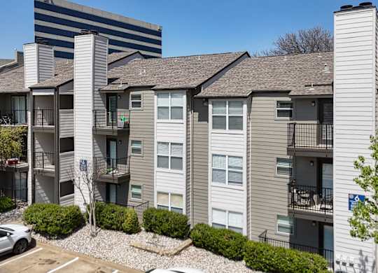 An apartment building with gray and white walls and balconies at The Park on Preston Apartments in Dallas, TX