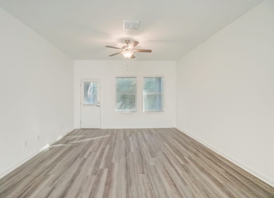 an empty living room with a ceiling fan and wood floors