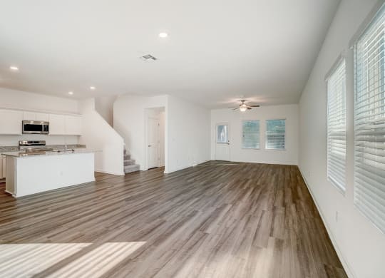 an empty living room and kitchen with wood flooring
