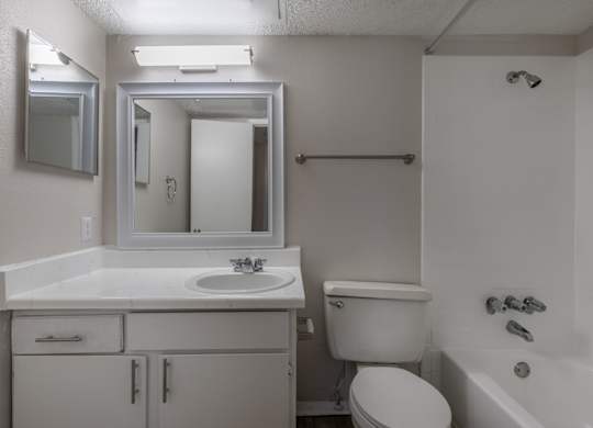 A white bathroom with a sink, toilet, and bathtub at Preston Oaks Apartments in Dallas, TX.