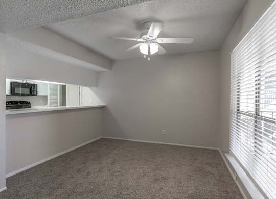 A dining room with a ceiling fan and carpeted floor at Preston Oaks Apartments in Dallas, TX.