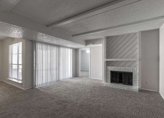 A living room with a fireplace and sliding glass doors at Preston Oaks Apartments in Dallas, TX.
