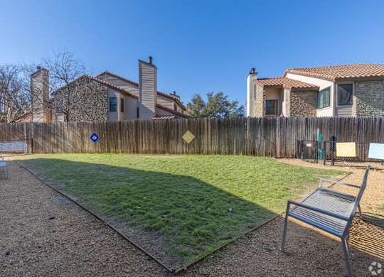 A dog park with a wooden fence and a bench at Preston Oaks Apartments in Dallas, TX.