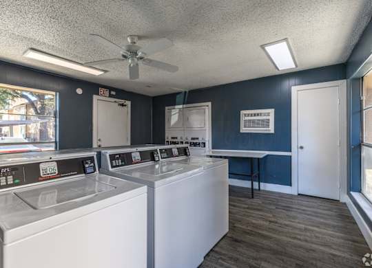 A laundry facility with washers and dryers at Preston Oaks Apartments in Dallas, TX.