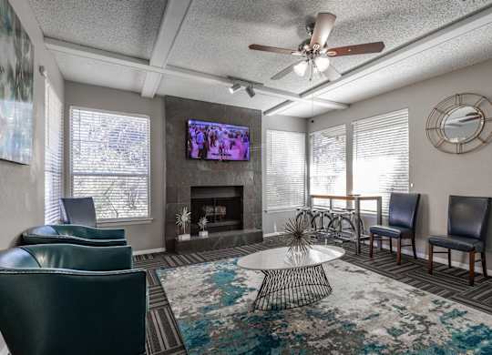 A leasing office with a fireplace, chairs, and a television at Preston Oaks Apartments in Dallas, TX.