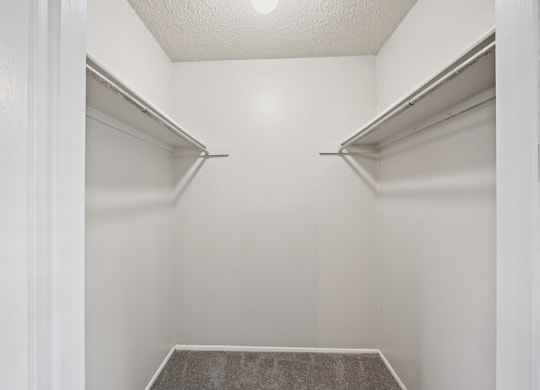 a walk in closet in a bedroom with white walls and a white ceiling