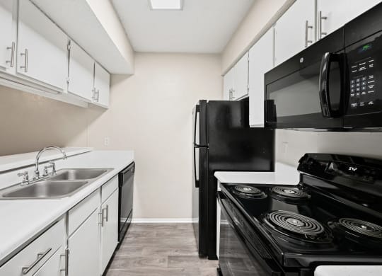 a kitchen with white cabinets and black appliances