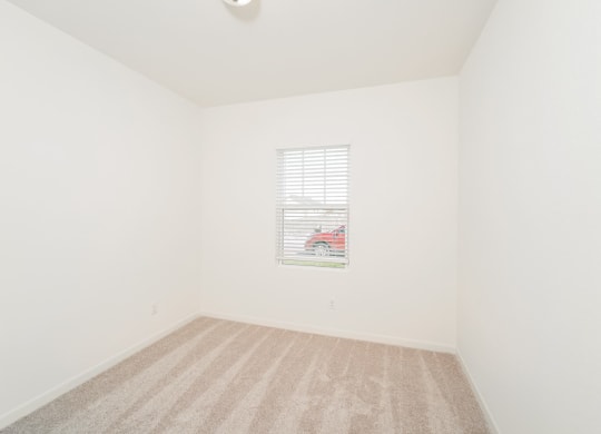 a bedroom with white walls and a window with a red car in it at Beacon at Meridian, San Antonio