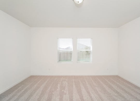 a bedroom with two windows and a carpeted floor at Beacon at Meridian, San Antonio, TX 78245