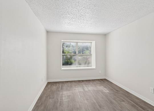 A room with a window and wooden flooring.