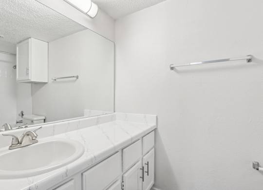 A white bathroom with a sink and a mirror.
