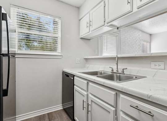 A kitchen with white cabinets and a black refrigerator.