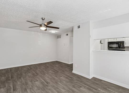 A room with a ceiling fan and wooden flooring.