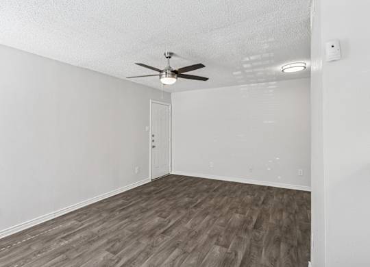 A living room with a ceiling fan and wooden flooring.