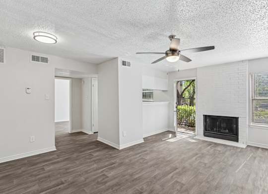 A spacious living room with a fireplace and a ceiling fan.