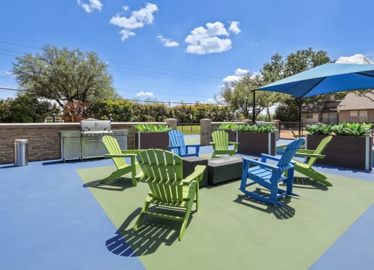a patio with green and blue chairs and a bbq grill