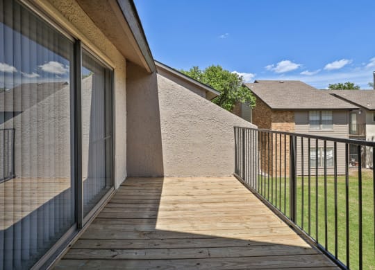 a balcony with a wooden deck and a glass sliding door
