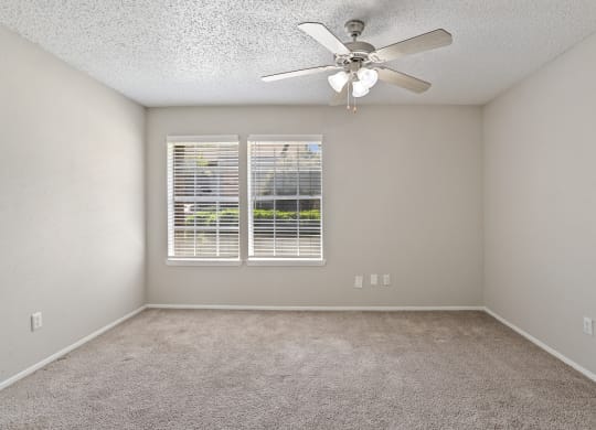 a bedroom with a ceiling fan and two windows