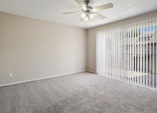 an empty bedroom with a ceiling fan and blinds