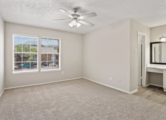 a bedroom with a large window and a ceiling fan