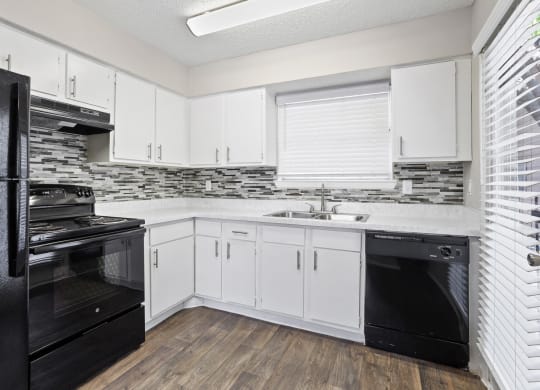 a kitchen with white cabinets and black appliances