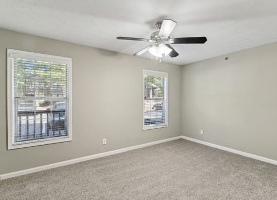 Unfurnished bedroom with plush carpeting, a ceiling fan, and windows at Oakley Run apartments in Smyrna, GA
