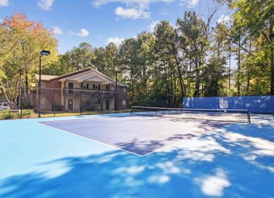 Blue tennis court with apartment building in the background at Oakley Run apartments in Smyrna, GA