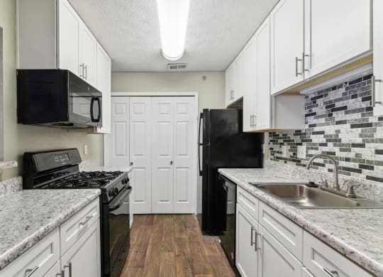 Apartment kitchen with white cabinets and black appliances at Oakley Run apartments in Smyrna, GA
