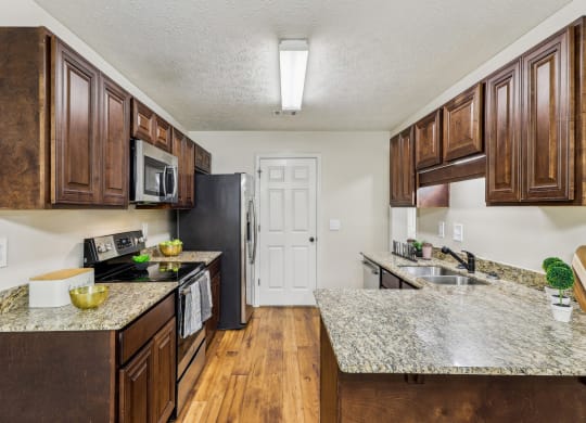 a kitchen with wooden cabinets and granite counter tops  at Grand Reserve Columbus in Columbus, GA