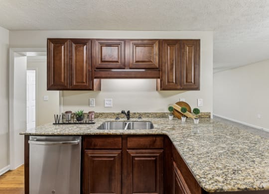 a kitchen with a granite counter top and a stainless steel sink  at Grand Reserve Columbus in Columbus, GA